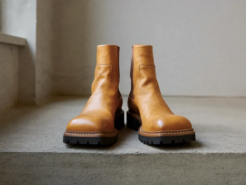 Hellbraune Stiefeletten mit profilierter Sohle auf rauer Betonstufe